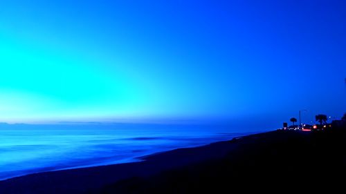 Long exposure of beach shore during first light of the sunrise with city lights in the background