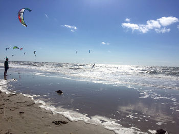 People enjoying at beach against sky