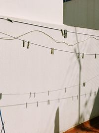 Low angle view of power lines against white wall