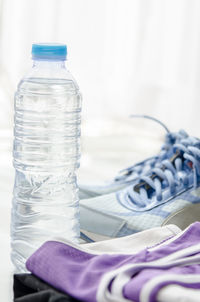 Close-up of water bottle with shoes and clothing on table