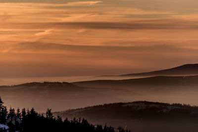 Scenic view of silhouette mountains against orange sky