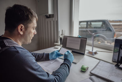 Person wearing gloves works on a laptop, signifying a high-tech or research-driven environment