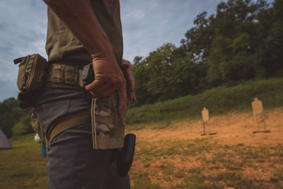 Midsection of man holding umbrella on field