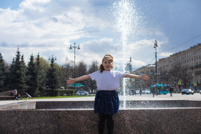 Happy little cute girl having fun in splashes a fountain