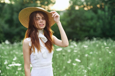 Young woman wearing hat standing against plants