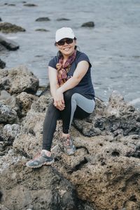 Portrait of woman with hands clasped sitting on rock