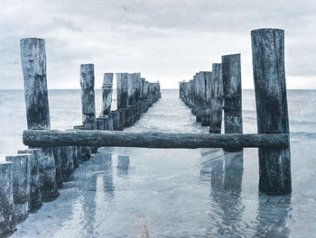 Baltic sea after overcast sunrise, old wooden breakwater in the light of the hidden sun, moody 