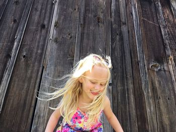 Low angle view of girl against wooden cottage