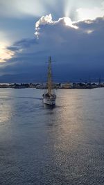 Sailing ship in sea against cloudy sky