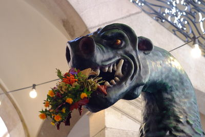 Close-up of dog statue by flowers