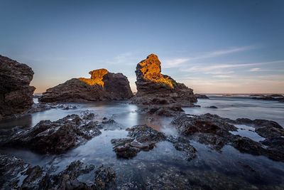 Rock formations in sea against sky