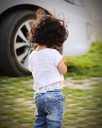 Rear view of woman standing by car