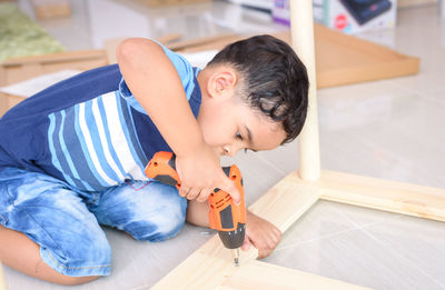 Boy drilling wood at home