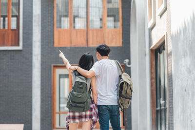 Rear view of people standing in front of building