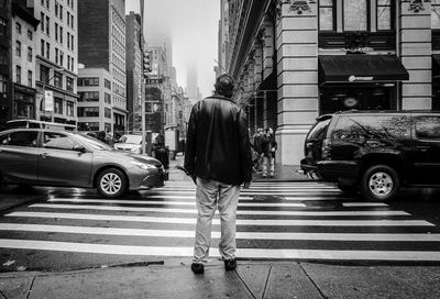 Rear view of man waiting at crosswalk