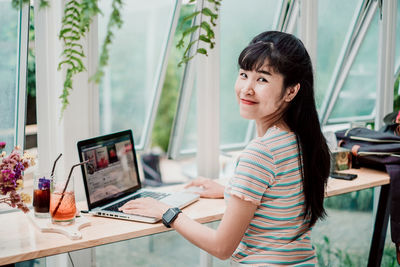 Side view of woman using mobile phone at table