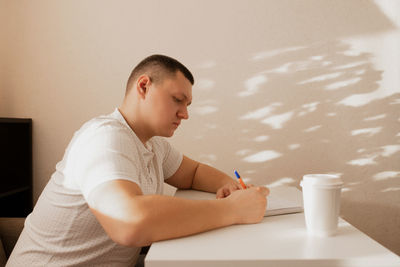 Side view of man writing in notepad at cafe