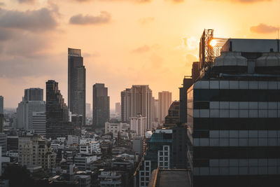 Modern buildings in city against sky during sunset