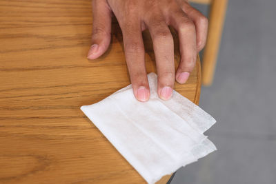 Close-up of hand holding paper on table