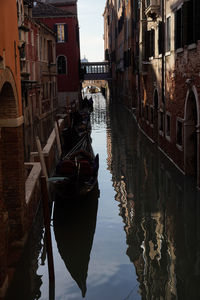 Boats moored in canal amidst buildings in city