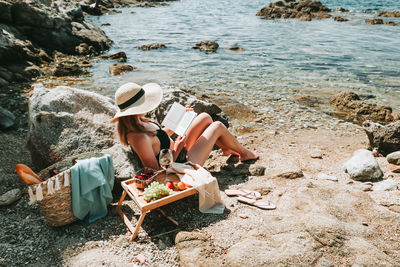 People relaxing on rock at beach