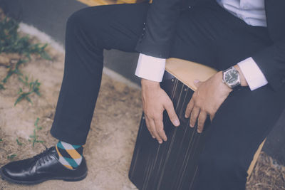 Low section of man in suit sitting on stool