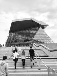 Rear view of people walking on staircase against building