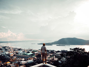 Rear view of man standing by sea against sky