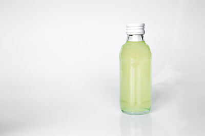 Close-up of glass bottle on table against white background
