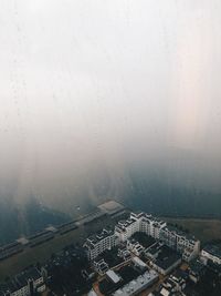 Aerial view of city buildings seen through wet window