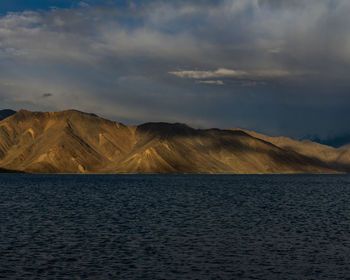 Scenic view of sea by mountains against sky