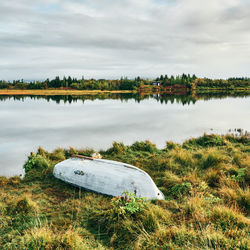 Shabby overturned boat on lonely lake shore