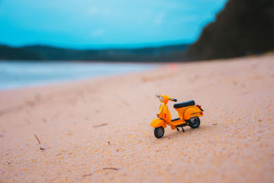Toy car on sand at beach against sky