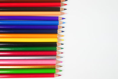 Close-up of colored pencils over white background