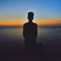 Silhouette of people on beach at sunset