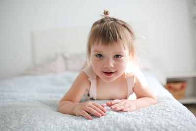 Happy funny girl toddler lifestyle with a smile lying on the bed, close-up, 