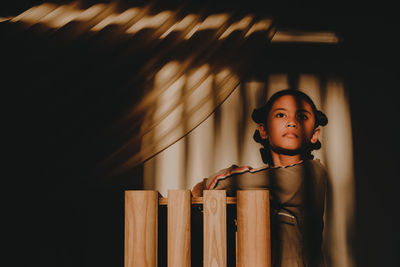 Sunlight falling on girl standing by wall