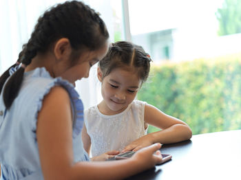 Sibling using smart phone while sitting at table