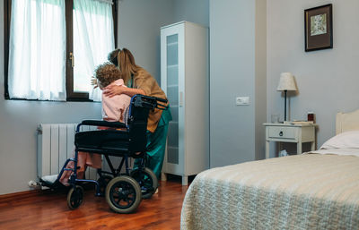 Mother and daughter sitting on bed at home