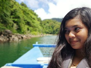 Close-up of smiling teenage girl looking away on boat in lake