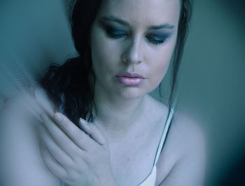 Close-up of thoughtful young woman against blue background