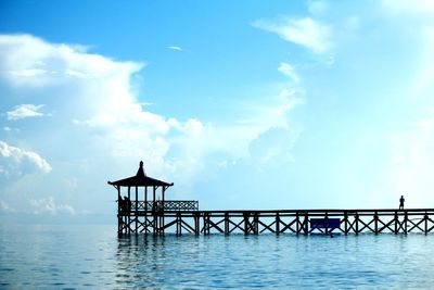 Silhouette pier over sea against blue sky