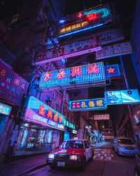 Illuminated street amidst buildings in city at night