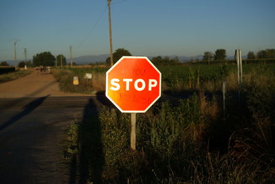 Close-up of road sign on field against clear sky