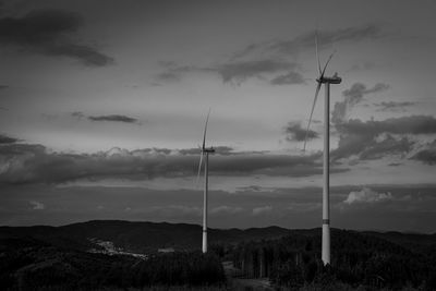 Wind turbines on landscape against sky