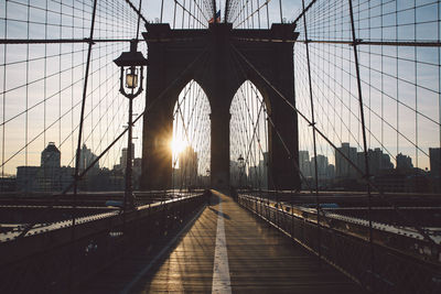 Silhouette suspension bridge against sky during sunset