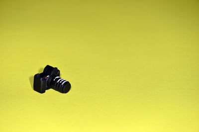 Close-up of miniature camera over yellow background