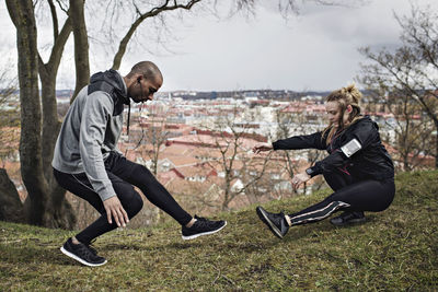 Full length of couple in sportswear exercising on hill