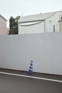 Road sign by building against clear sky