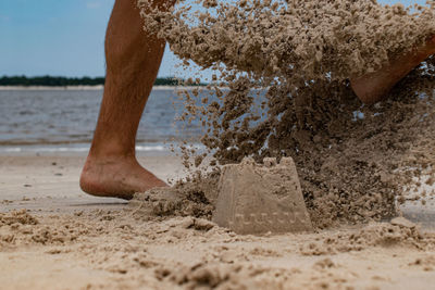 Kicking sandcastle on the beach